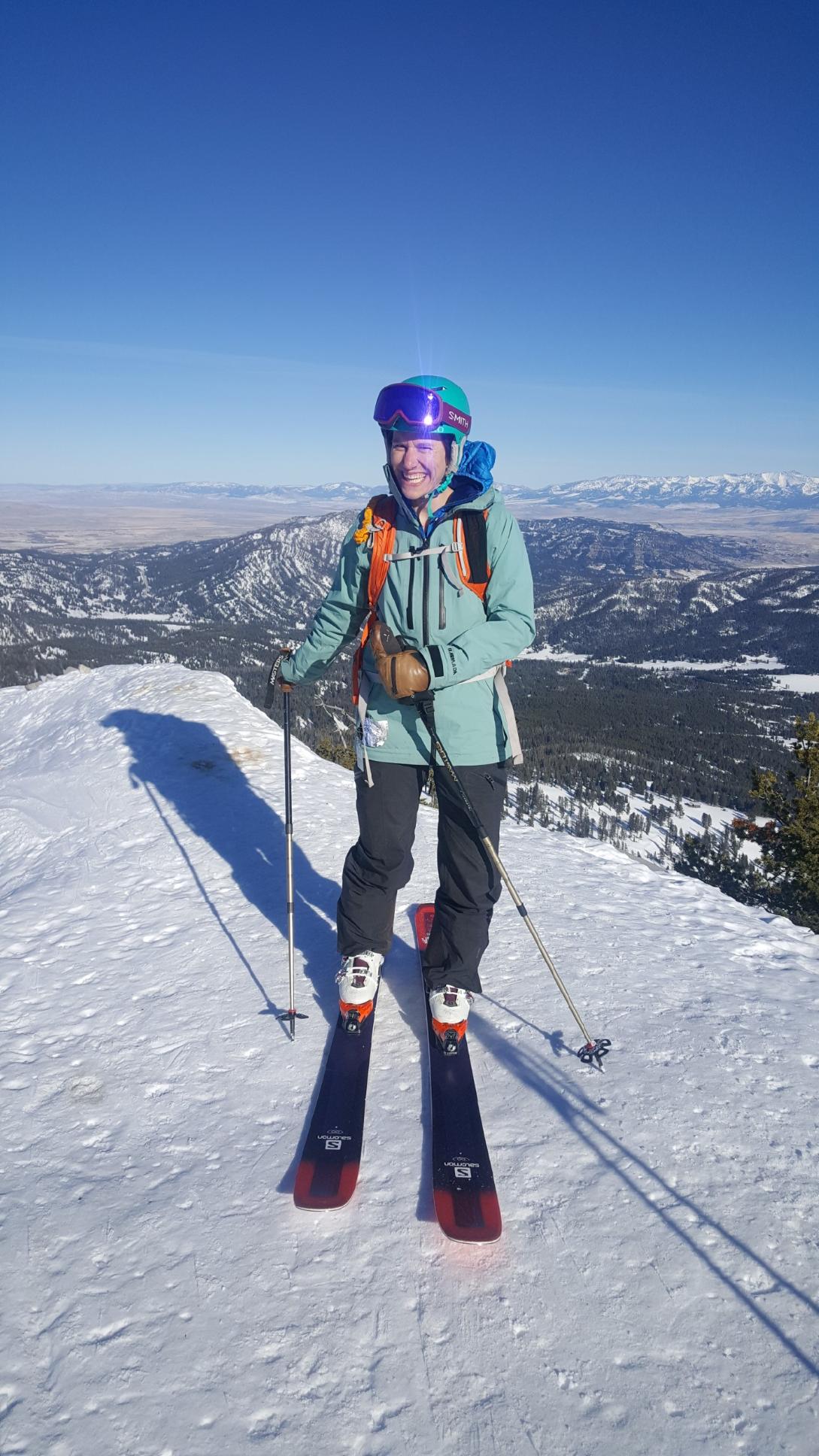 Dr. Theobold standing at the top of a snowy mountain with skis and poles!