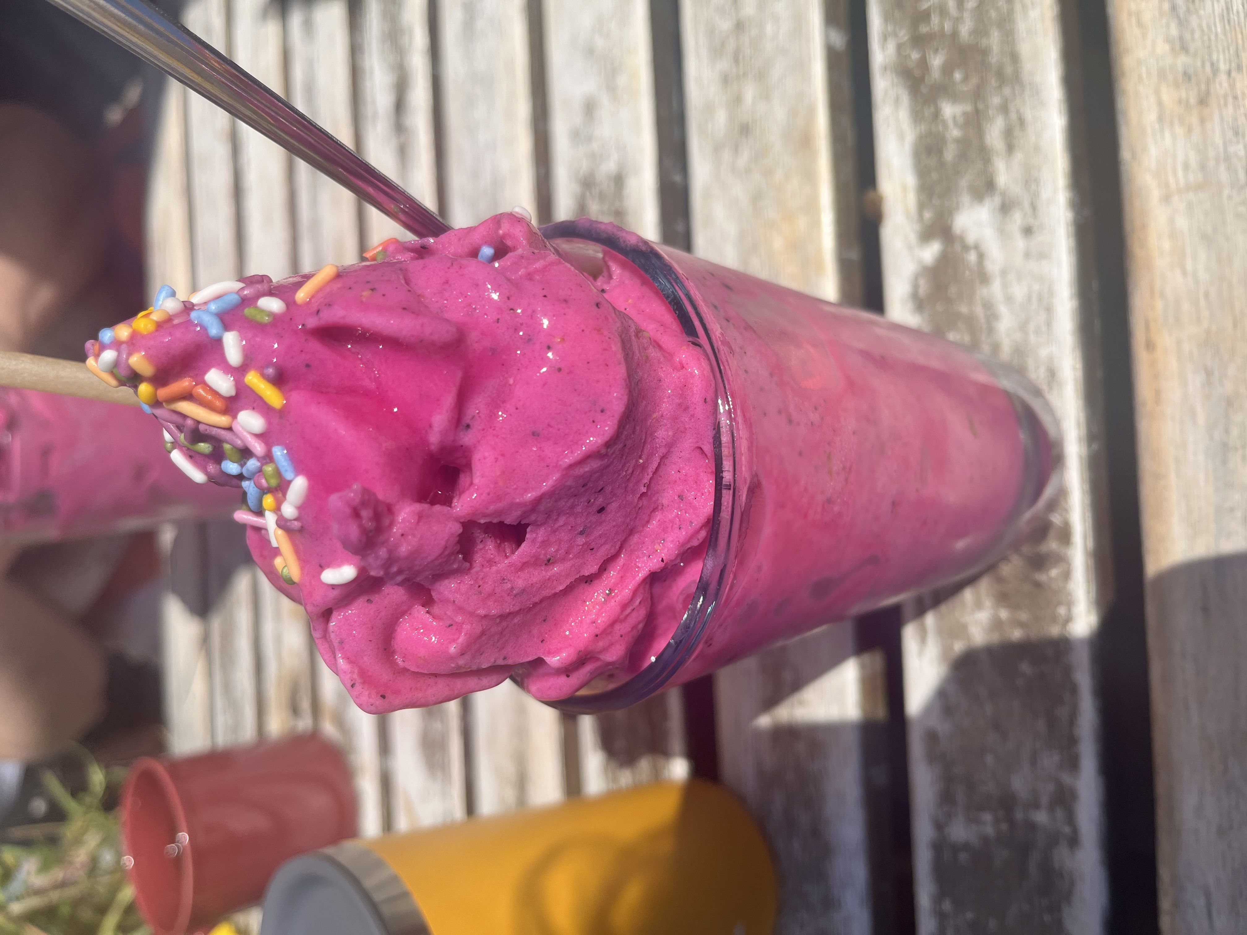 A picture of a very pink fruit smoothie, with sprinkles on top.