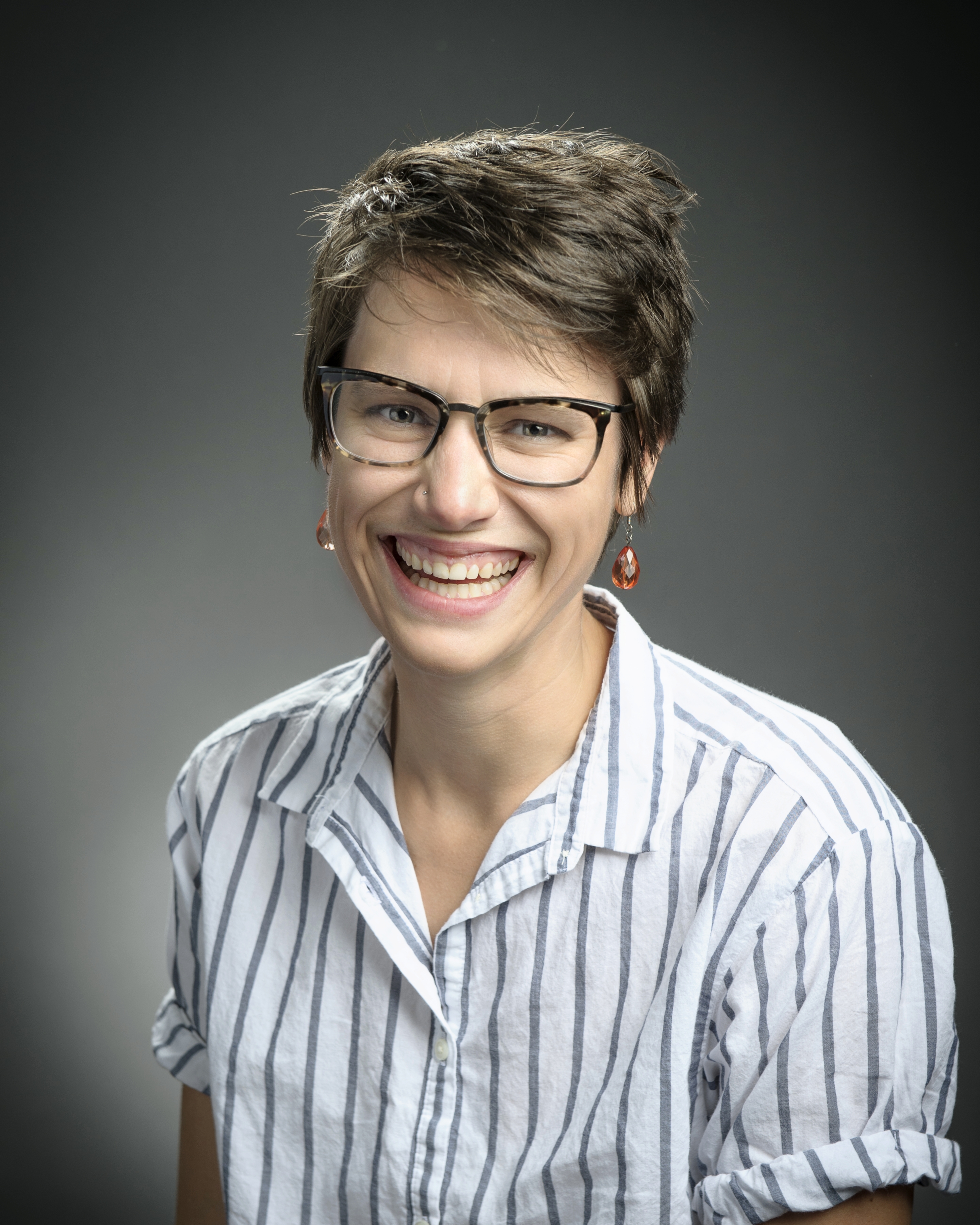 A headshot of Allison Theobold -- also styling tourtise glasses and a casual striped button down shirt.