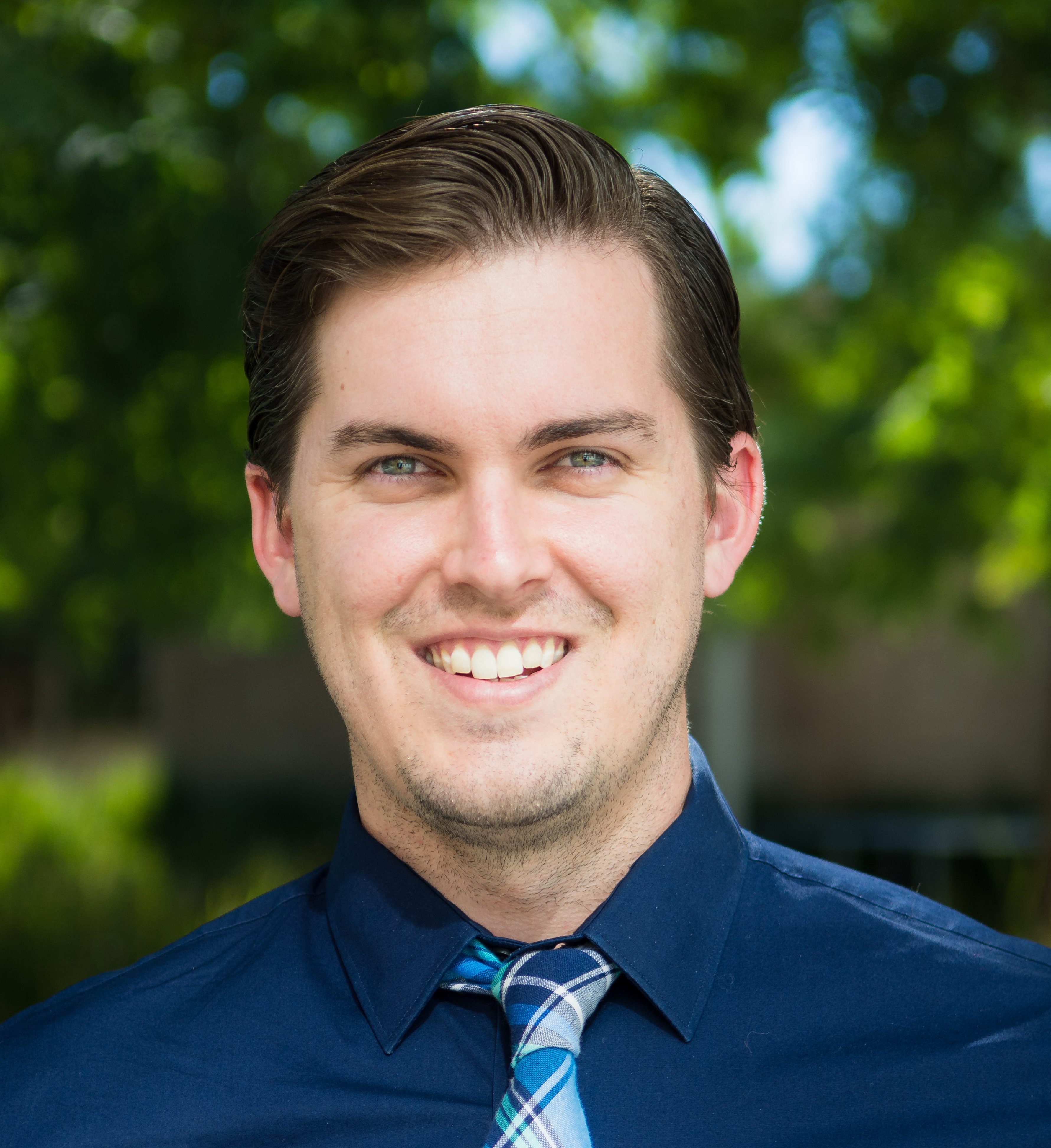 A headshot of Hunter Glanz -- looking dashing in a dark blue shirt and tie.